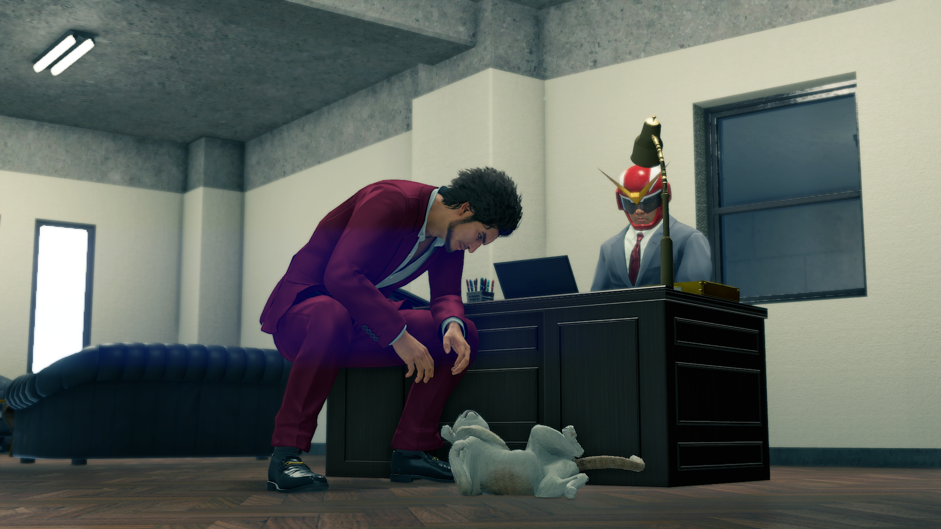 Screengrab of a cutscene from the game Yakuza: Like a Dragon, where Ichiban Kasuga, the game's protagonist, is seen squatting to look at a cat that is on its back and is showing its belly to him. In the background you can also see Part-Time Hero, who is the owner of the cat, behind an office desk.