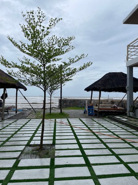 View of the backyard of a rest house in Zambales, Philippines. This was taken while there was a typhoon leaving the country, and part of the typhoon's tail was around the area, bringing cloudy skies, strong wind, and constant rain that would strengthen or weaken depending on the hour. Over the distance, the sea is at high tide, brought about the effects of the typhoon.