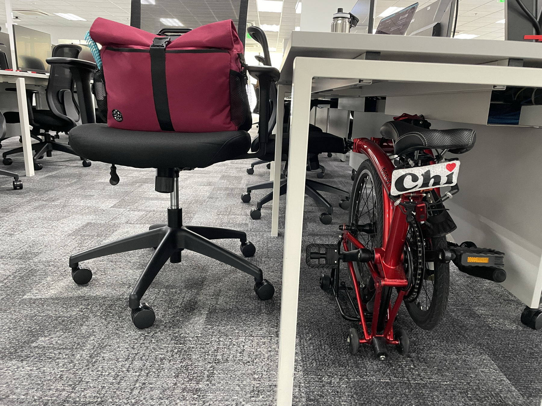 Chi’s trifold bike in the fully folded state fitted under her table at the office, and her bike bag placed on her computer chair.