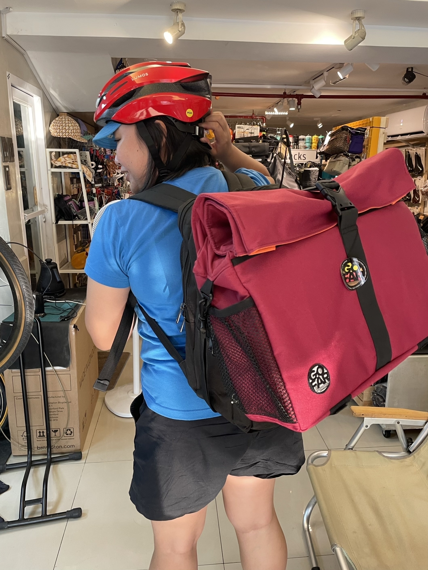 photo of Chi with her backpack on, and her new front bag, meant for a trifold folding bike with a front carrier block, attached to the front of her backpack.