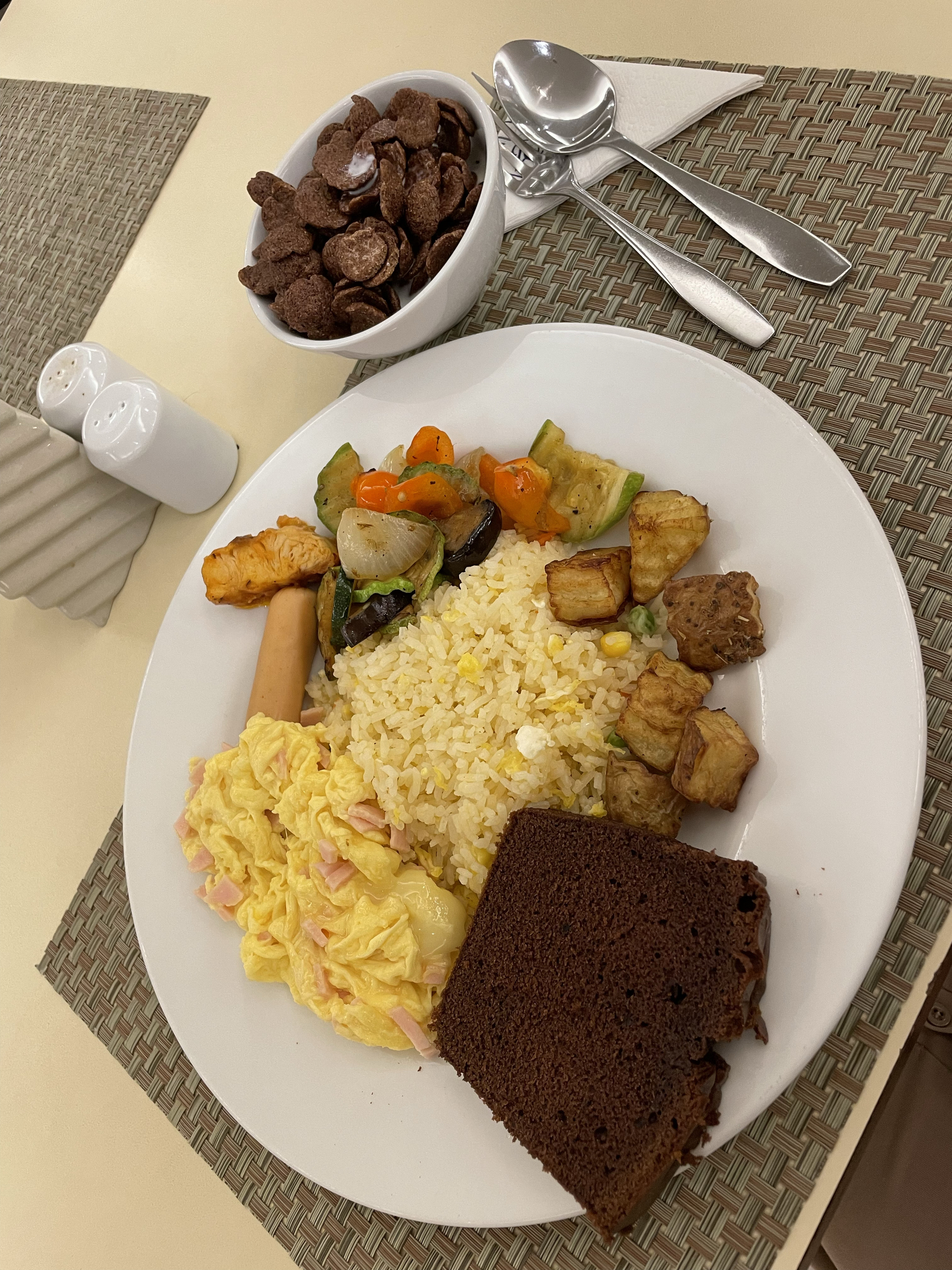 Chi’s breakfast from the hotel: scrambled egg with ham and cheese, a chicken sausage, some steamed vegetables, sweet and sour fish, with egg fried rice and a brownie. She also has a bowl of Koko Crunch chocolate cereal.