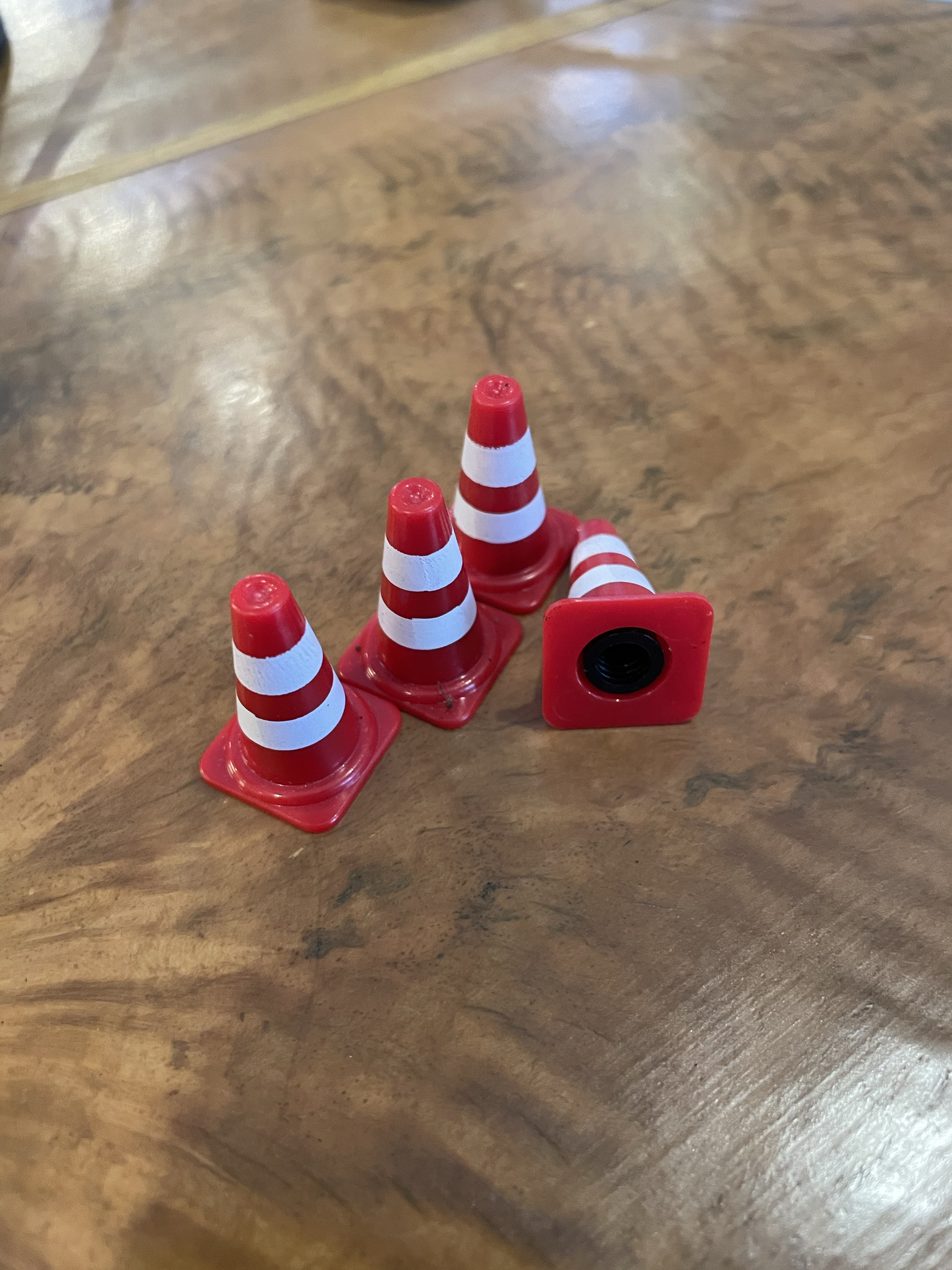 photo of 4 3d-printed traffic cone valve caps on a table, with 1 tipped over to show the valve cap part