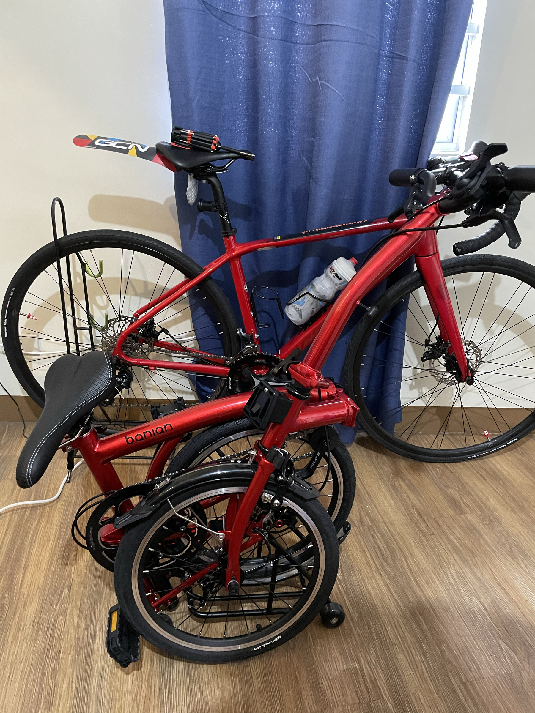 photo of Chi’s two bikes, a red Merida Scultura 200 Disc road bike at the back, and a folded Banian Trifold 16